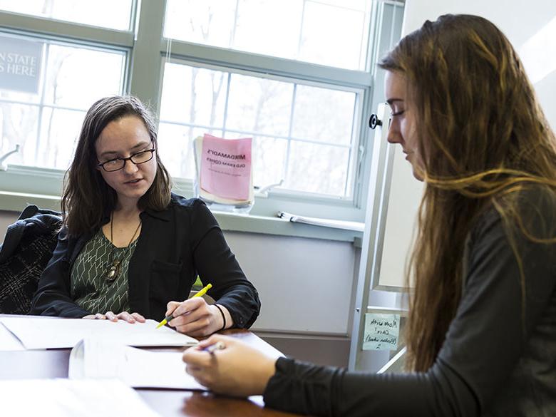 Female student works on paperwork with help from female 工作人员 member